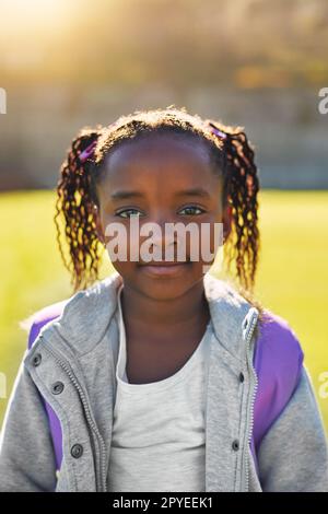 Shes prêt à apprendre et à exceller à l'école. Portrait d'une fille de l'école élémentaire debout à l'extérieur. Banque D'Images