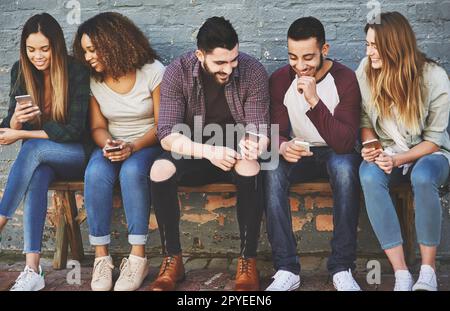 Communiquer avec l'équipage. un groupe de jeunes amis utilisant leur téléphone mobile à l'extérieur. Banque D'Images