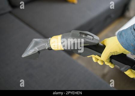 Homme dans le canapé de nettoyage de gants en caoutchouc de protection avec la méthode d'extraction professionnelle avec aspirateur de lavage. Nettoyage régulier au début du printemps. Concept d'entreprise de nettoyage commercial Banque D'Images