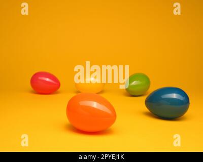 Oeufs de Pâques en plastique coloré sur un fond de studio jaune Banque D'Images