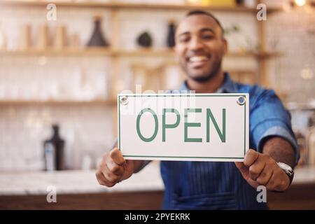 C'est agréable de vous revoir ici. Portrait d'un jeune homme tenant une affiche ouverte dans son magasin. Banque D'Images