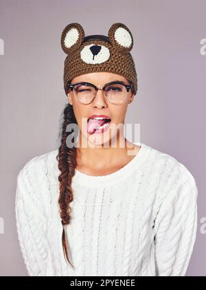 Devinez mon animal d'esprit. Photo studio d'une jeune femme portant un bonnet en forme d'ours en peluche marron. Banque D'Images