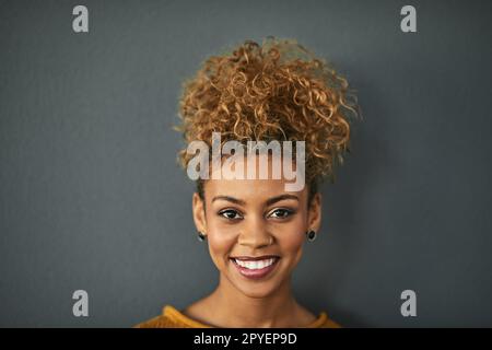 C'est une dame qui a du bonheur. Portrait studio d'une jeune femme attrayante debout sur fond gris. Banque D'Images