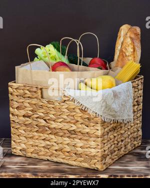 Légumes frais, légumes verts et fruits, céréales et pâtes dans un panier en osier. Livraison ou don de concept alimentaire. Banque D'Images