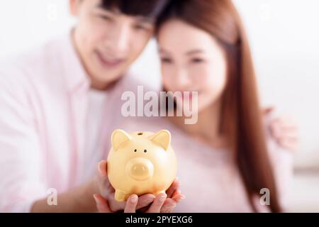 Couple heureux tenant Piggybank et faisant des économies pour l'avenir Banque D'Images