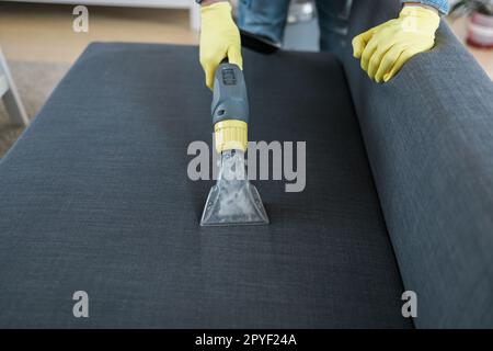 Homme nettoyant canapé avec aspirateur, gros plan Banque D'Images