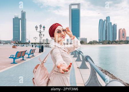 Une fille indienne marche le long du remblai d'Abu Dhabi, profitant de la vue magnifique et de l'atmosphère sereine de la ville. Suivez-moi pose. Banque D'Images