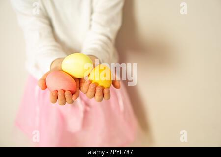 Les mains des enfants ont trois œufs de Pâques colorés. Joyeuses Pâques. Préparation pour Pâques et le printemps. Banque D'Images