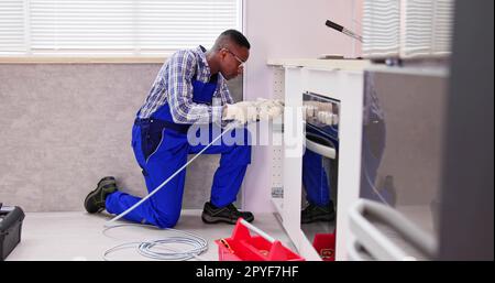 Jeune homme plombier nettoyant le tuyau d'évier bouché Banque D'Images