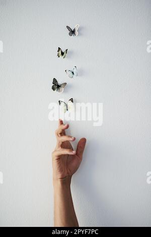 Laissez vos rêves prendre l'envol. Photo en studio d'une personne méconnaissable libérant des papillons dans l'air sur un fond gris. Banque D'Images