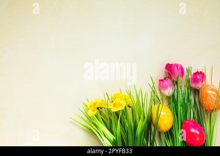 Œufs de pâques colorés avec fleurs et herbe verte. Les œufs de Pâques disparaissent sur fond jaune clair. . Vacances de Pâques, concept de chasse aux œufs Banque D'Images