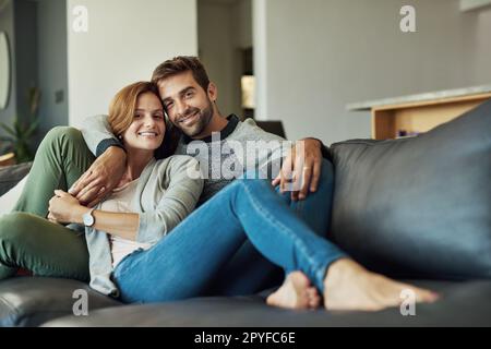 C'est ici que vous nous trouverez ce week-end. Portrait en longueur d'un jeune couple affectueux qui se détend sur son canapé à la maison. Banque D'Images