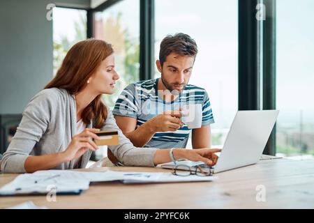 Essayer de rester avec dans notre budget. un jeune couple qui travaille sur le budget de son ménage et qui paie ses factures en ligne. Banque D'Images