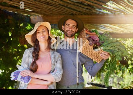 Ne paniquez pas, ça n'est pas bio. Portrait d'un couple heureux travaillant ensemble dans un potager. Banque D'Images