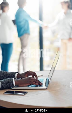 Se connecter de plusieurs façons. un jeune homme d'affaires inidentifiable travaillant sur son ordinateur portable à une table au bureau. Banque D'Images