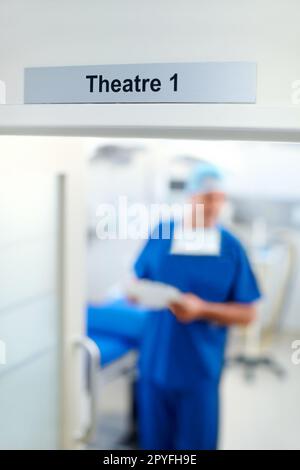 Théâtre 1, où le médecin sauve des vies. Image floue d'un médecin portant des gommages sous un signe focalisé de lecture Theatre 1. Banque D'Images