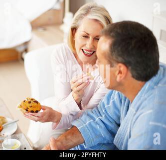 Bonne humeur femme mature nourrissant Muffin à son mari. Portrait d'une femme mûre et gaie qui allaite Muffin à son mari. Banque D'Images