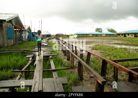 Ondo State, Nigeria - 2 mai 2023 - Un garçon qui marche à travers un bidonville pollué dans la communauté fluviale d'Abereke de l'État d'Ondo. Banque D'Images