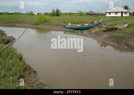 Ondo State, Nigeria - 2 mai 2023 - Un homme assis sur un bateau entouré d'eau polluée par le pétrole à Abereke, communauté fluviale d'Ilaje. Banque D'Images