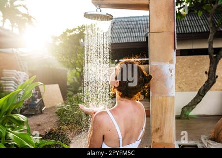 Femme prenant une douche extérieure dans une station de vacances de rêve. Banque D'Images
