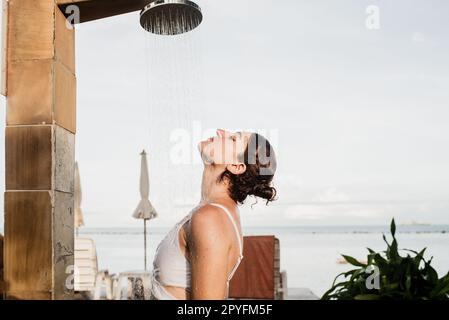 Femme prenant une douche extérieure dans une station de vacances de rêve. Banque D'Images