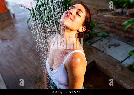 Femme prenant une douche rafraîchissante en plein air dans une station de vacances de rêve. Banque D'Images