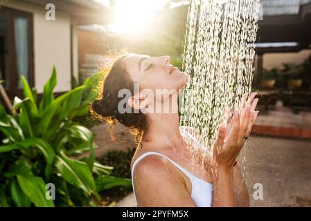 Femme prenant une douche extérieure dans une station de vacances d'été de rêve. Banque D'Images
