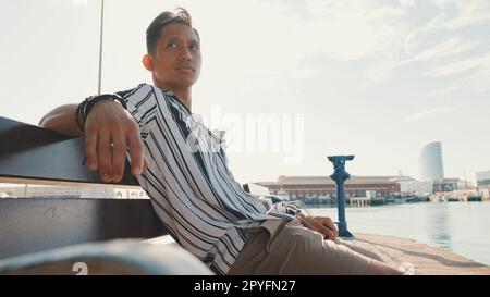 Un jeune touriste est assis sur un banc sur la jetée Banque D'Images