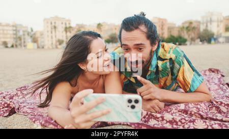 Homme et femme effectuant un appel vidéo à l'aide d'un téléphone portable sur la plage Banque D'Images