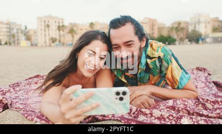 Homme et femme effectuant un appel vidéo à l'aide d'un téléphone portable sur la plage Banque D'Images