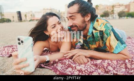 Homme et femme effectuant un appel vidéo à l'aide d'un téléphone portable sur la plage Banque D'Images