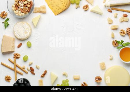 Cadre composé de différents types de fromage savoureux, de noix et de miel sur fond clair Banque D'Images