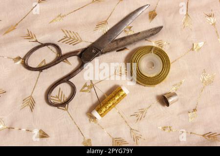 Bobine de fil d'or et ciseaux avec Thimble sur tissu métallique Banque D'Images