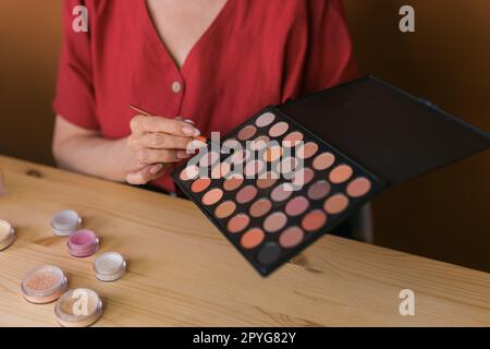 Gros plan de la femme tenant le pinceau à maquillage et la palette de fard à joues et de fards à paupières - concept de beauté et de cosmétiques Banque D'Images