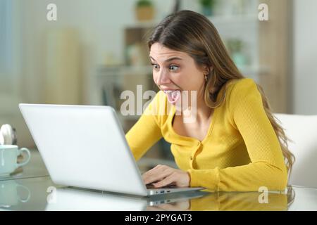 Femme étonné vérifiant le contenu de l'ordinateur portable à la maison Banque D'Images