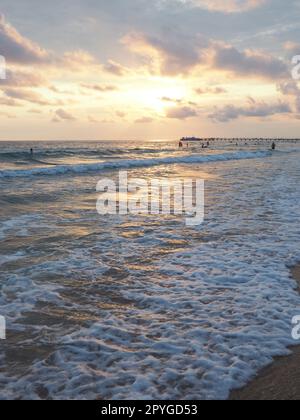 Vague et coucher de soleil sur la mer. Magnifique coucher de soleil. Les vagues mousseuses roulent sur le rivage sablonneux. Vityazevo, Anapa, Mer Noire. Mecque touristique, station thermale. Ciel du soir. Les rayons se réfléchissent sur l'eau. Banque D'Images