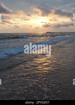 Vague et coucher de soleil sur la mer. Magnifique coucher de soleil. Les vagues mousseuses roulent sur le rivage sablonneux. Vityazevo, Anapa, Mer Noire. Mecque touristique, station thermale. Ciel du soir. Les rayons se réfléchissent sur l'eau. Banque D'Images