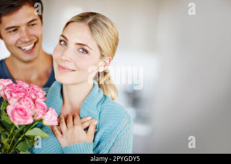 Amour fleuri. un jeune homme affectueux donnant à sa belle jeune femme un bouquet de roses roses. Banque D'Images