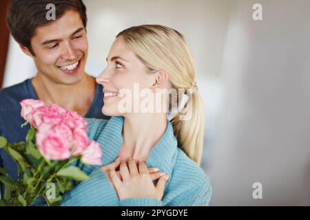 Leur amour est en fleur. un jeune homme affectueux donnant à sa belle jeune femme un bouquet de roses roses. Banque D'Images