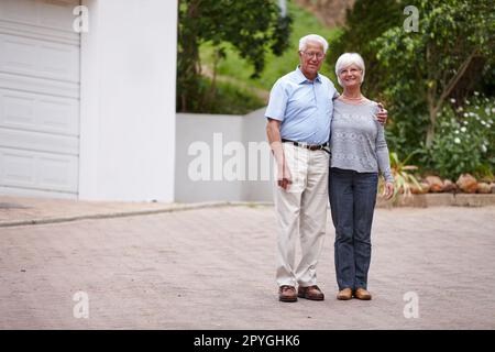 Dans mes bras pour seulement un moment, mais dans mon cœur pour toujours. un heureux couple senior debout à l'extérieur tout en souriant à la caméra. Banque D'Images