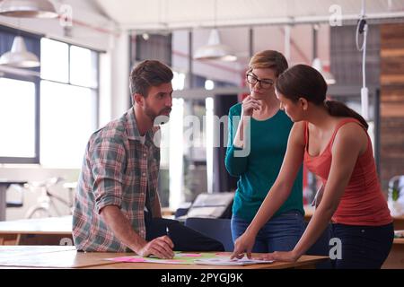 Le travail d'équipe fait le travail de rêve. Un groupe de jeunes créatifs qui parlent autour d'une table. Banque D'Images