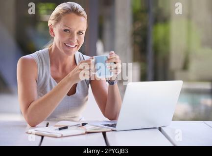 Prendre un café pendant que je travaille. Portrait rogné d'une femme d'affaires attirante travaillant sur son ordinateur portable. Banque D'Images
