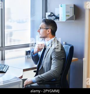 Se préparer à son évaluation de rendement. un homme d'affaires qui ajuste sa cravate en étant assis à son bureau. Banque D'Images