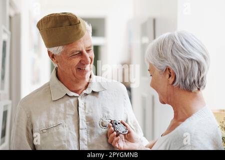 Vous méritez également une médaille pour le meilleur père et grand-père. Une femme âgée qui regarde ses maris médailles alors qu'il porte l'uniforme complet de son armée. Banque D'Images