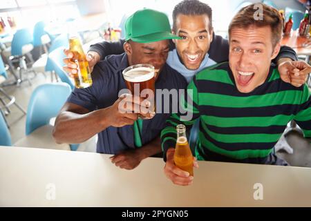 Ces garçons les renfendent rapidement. Vue de dessus d'un trois amis se détendre au bar avec de la bière. Banque D'Images