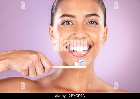 Femme, sourire et brosse à dents en studio portrait avec soins personnels, beauté et dentifrice pour l'hygiène. Femme noire, dents et nettoyage avec brosse en bois organique, heureux et amour de soi par fond violet Banque D'Images