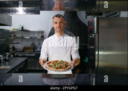 Pizzeria masculine proposant des pizzas fraîchement cuites Banque D'Images