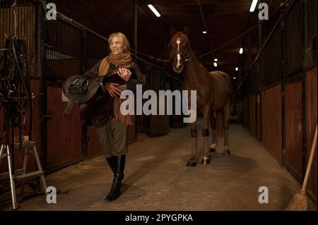 Cavalier femelle marchant avec harnais en stable Banque D'Images