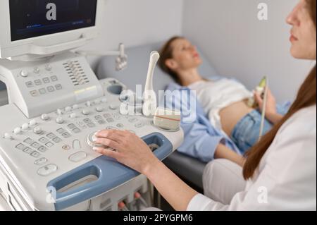 Focus sélectif médecin faisant l'échographie du fœtus à la femme enceinte Banque D'Images