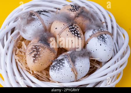 Composition de Pâques avec une couronne blanche décorative, œufs de caille sous forme de nid sur un jaune Banque D'Images